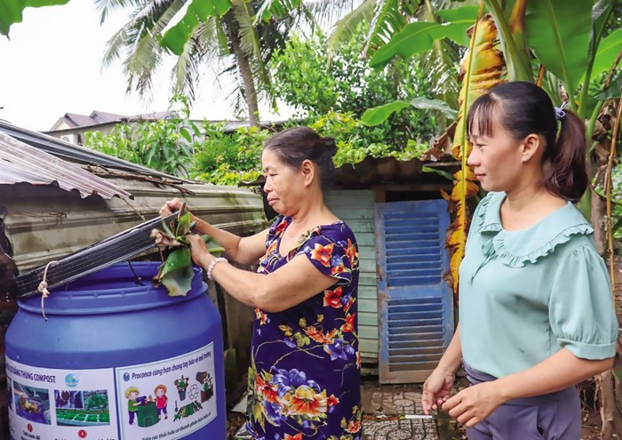 Cô Cánh (trái ảnh) hướng dẫn cách sử dụng thùng compost ủ phân hữu cơ của gia đình